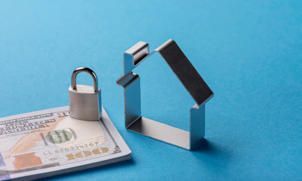 A stack of hundred-dollar bills with a silver padlock placed on top is next to a metal house-shaped outline, all set against a bright blue background. The image symbolizes financial security and home protection.