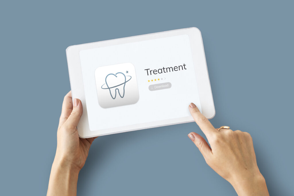 Image showing hands holding a tablet displaying a dental treatment application. The app icon features a tooth with a ring around it, symbolizing orthodontic care. The app title reads 'Treatment' with a download button below, representing a digital tool or application for dental or orthodontic treatment.